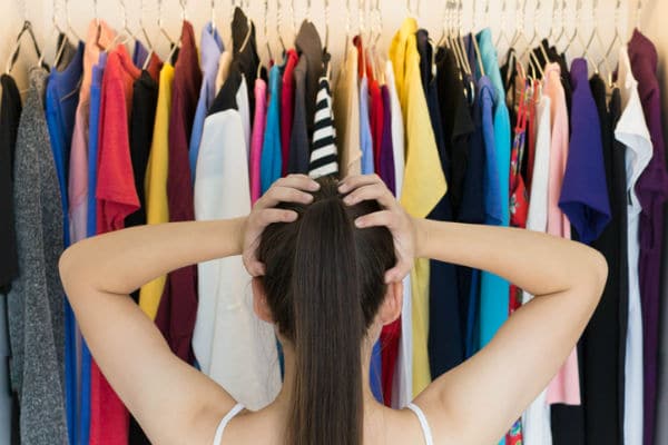 a woman worried about what she'll wear while looking at her wardrobe