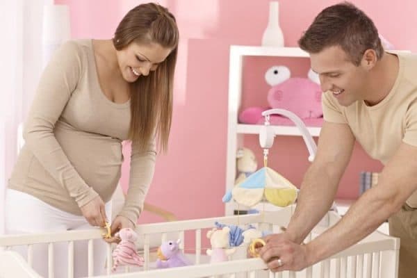 an expecting couple setting up their baby's crib