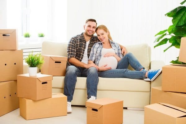 a pregnant wife and her husband sitting on the couch on moving day