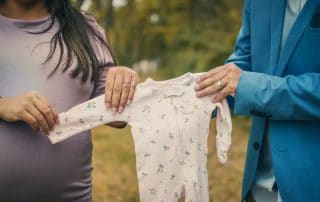 mum and dad holding baby clothes