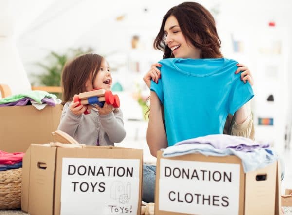 Mother and daughter preparing toys and clothes to donate for charity