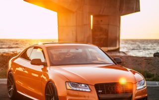 Orange Audi by the water under sunset