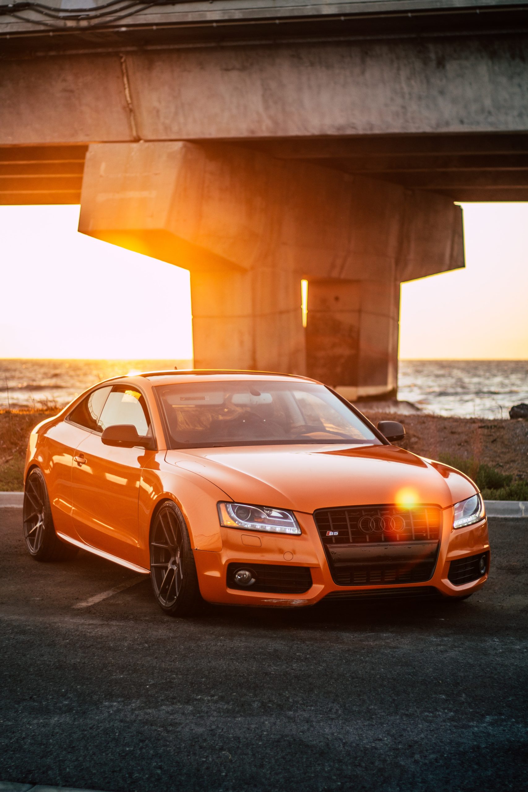 Orange Audi by the water under sunset