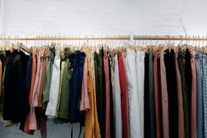assorted clothes on hangers hanging on wooden rack
